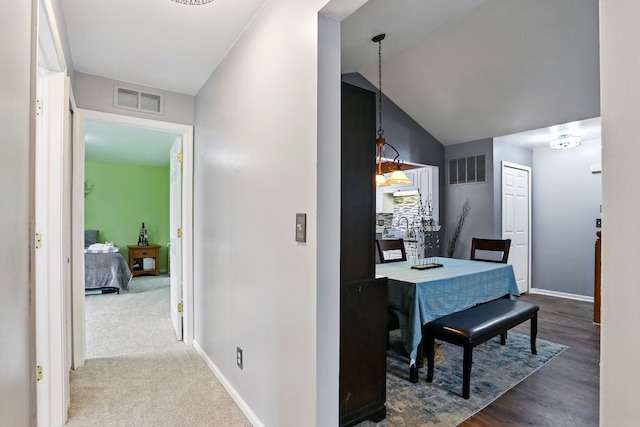 hall with baseboards, lofted ceiling, and wood finished floors