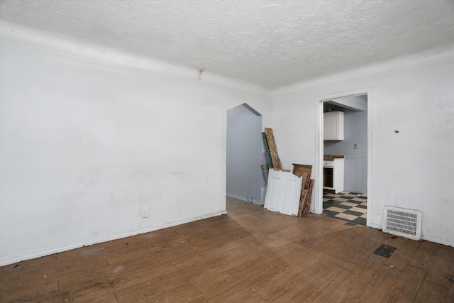 unfurnished room with a textured ceiling, visible vents, and hardwood / wood-style flooring