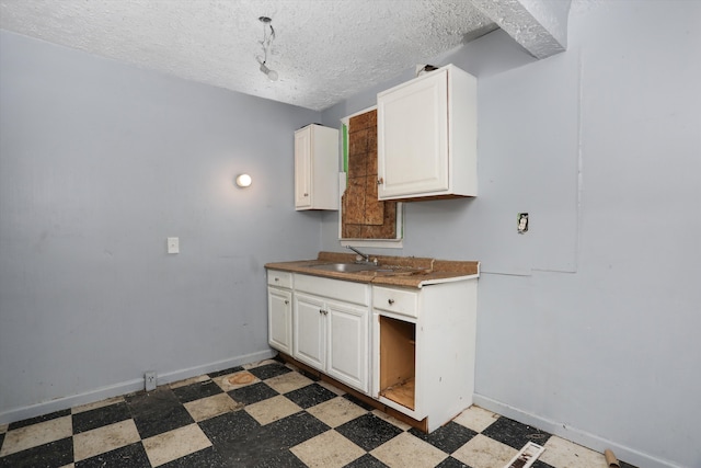 kitchen featuring a sink, white cabinets, tile patterned floors, and baseboards