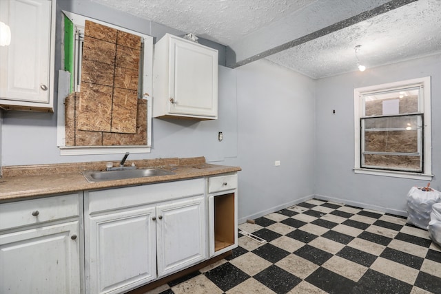kitchen featuring tile patterned floors, light countertops, white cabinets, a sink, and a textured ceiling