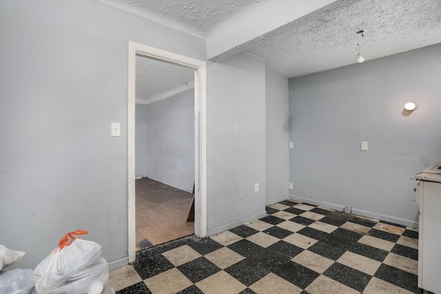 empty room with tile patterned floors, a textured ceiling, and baseboards