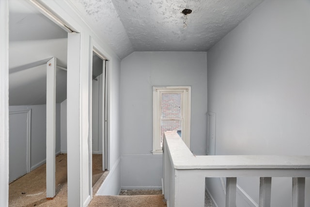 stairway with a textured ceiling and vaulted ceiling