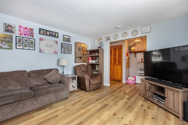 living area featuring a chandelier, light wood-style floors, and baseboards