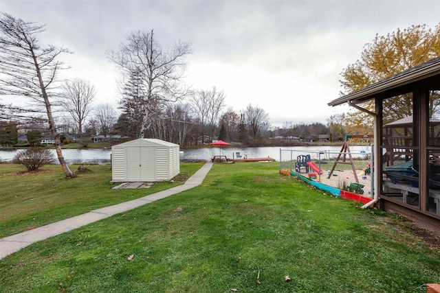 view of yard with a water view, a playground, a shed, and an outbuilding