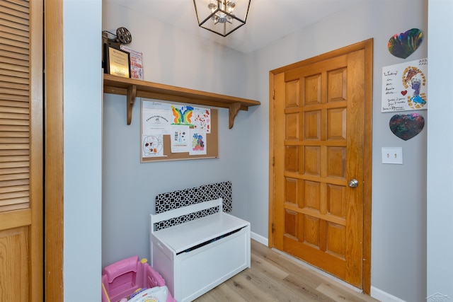 interior space featuring light wood-style flooring, an inviting chandelier, and baseboards