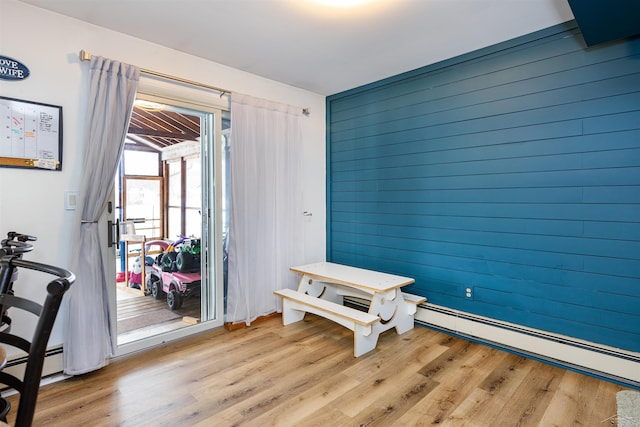 entryway with light wood-type flooring, wooden walls, and a baseboard radiator