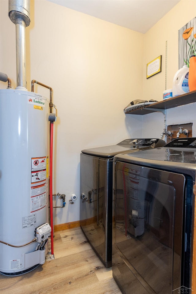 laundry area featuring water heater, baseboards, light wood-style floors, laundry area, and washer and dryer