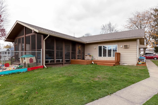 back of house with roof with shingles, a sunroom, and a lawn