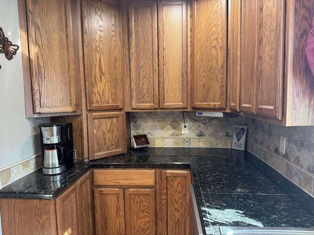 18175 Lake Dr, Big Rapids, MI 49307 - kitchen featuring brown cabinets, backsplash, and dark stone counters