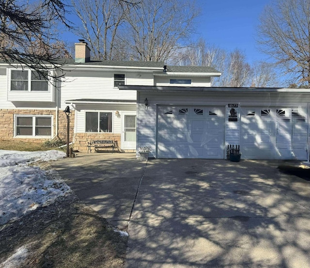 18175 Lake Dr, Big Rapids, MI 49307 - view of front of home with an attached garage, stone siding, driveway, and a chimney