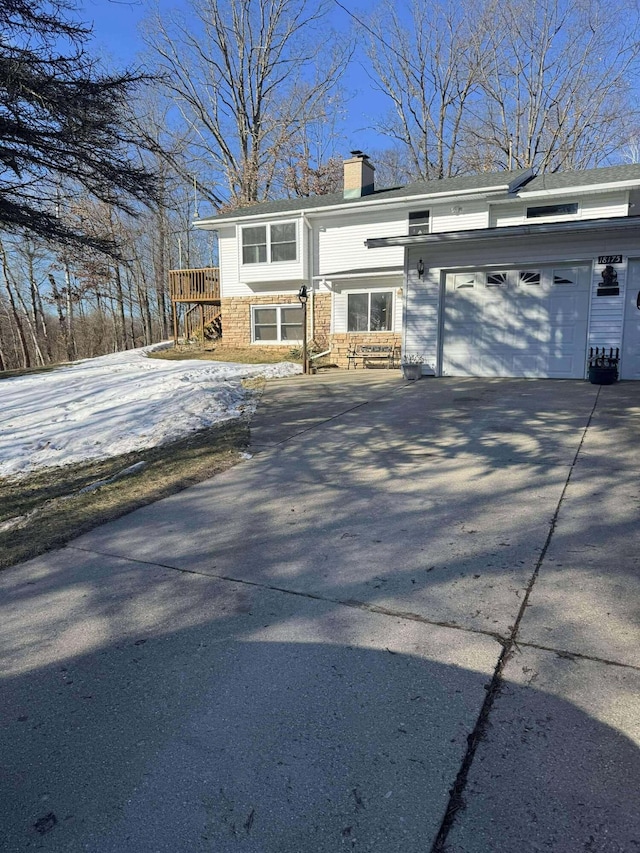 18175 Lake Dr, Big Rapids, MI 49307 - view of front facade featuring a garage, a chimney, and concrete driveway