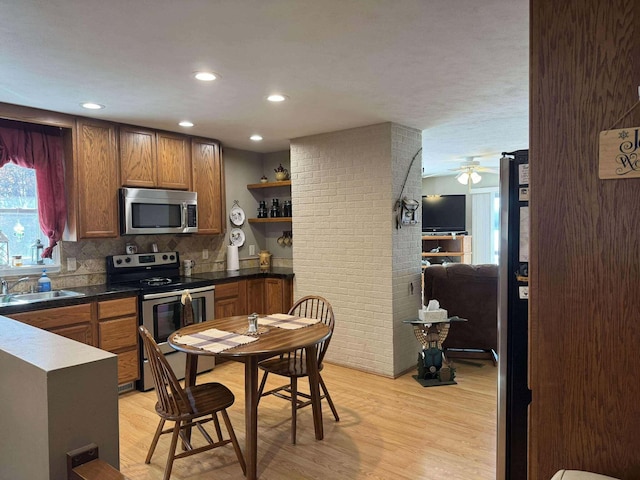 18175 Lake Dr, Big Rapids, MI 49307 - kitchen with light wood-style floors, open shelves, appliances with stainless steel finishes, a sink, and decorative backsplash