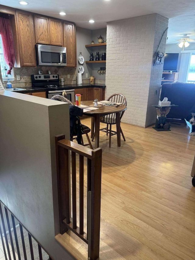 18175 Lake Dr, Big Rapids, MI 49307 - kitchen featuring light wood-style flooring, appliances with stainless steel finishes, dark countertops, and open shelves