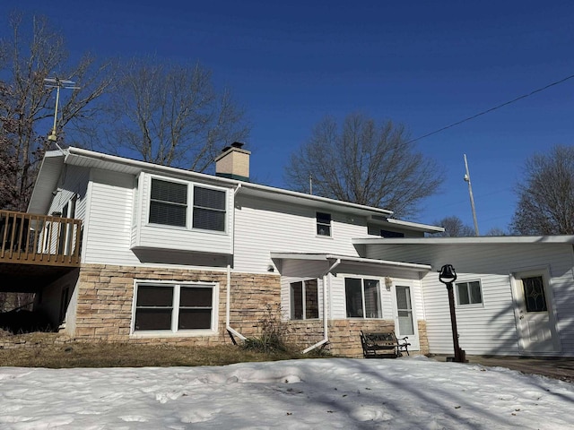 18175 Lake Dr, Big Rapids, MI 49307 - snow covered rear of property with a deck, stone siding, and a chimney