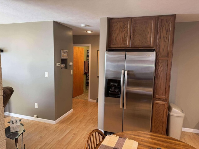 18175 Lake Dr, Big Rapids, MI 49307 - kitchen with light wood-type flooring, baseboards, stainless steel fridge, and dark brown cabinets
