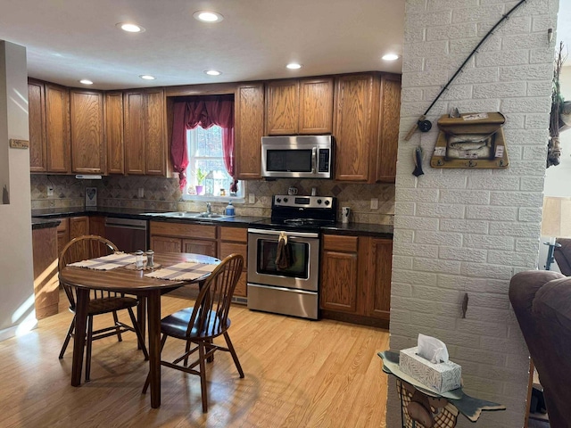 18175 Lake Dr, Big Rapids, MI 49307 - kitchen with dark countertops, backsplash, light wood-style flooring, and appliances with stainless steel finishes
