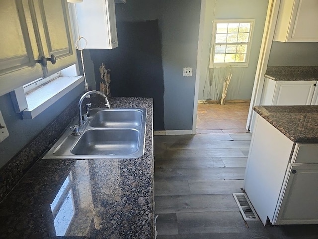 kitchen with white cabinets, visible vents, dark wood-style flooring, and a sink