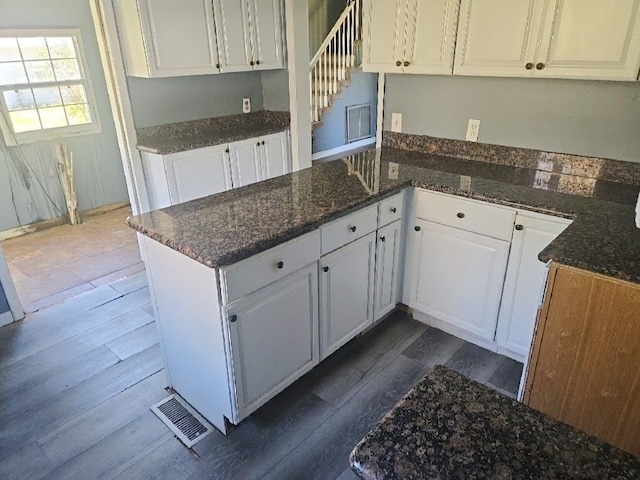 kitchen featuring visible vents, a peninsula, dark wood-style floors, and white cabinetry