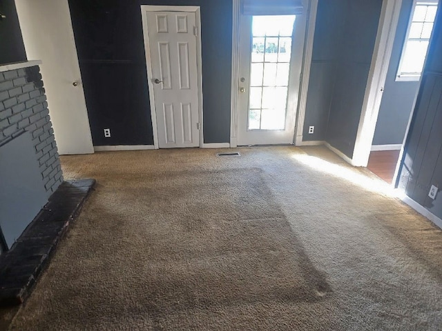 unfurnished living room with baseboards, carpet flooring, visible vents, and a fireplace