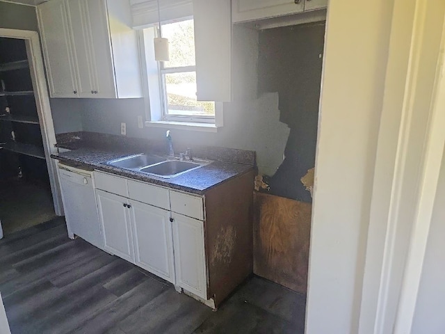 kitchen with white cabinets, dark wood finished floors, dark countertops, dishwasher, and a sink
