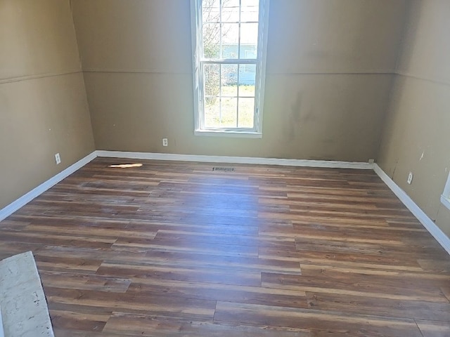 spare room with baseboards and wood finished floors