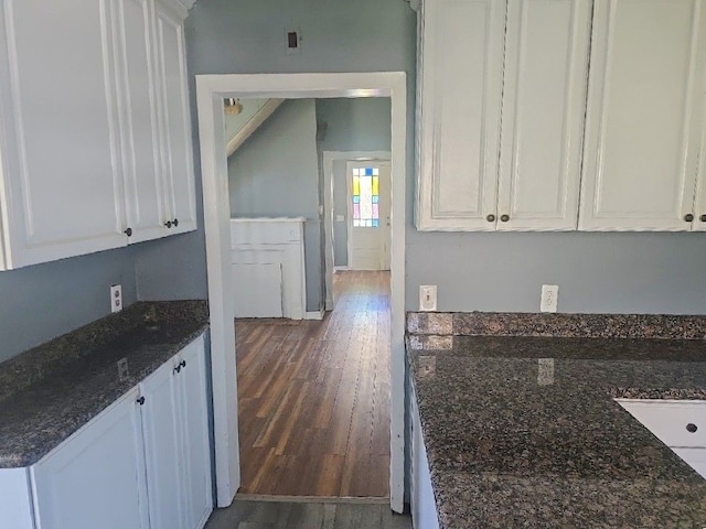 kitchen with white cabinets, wood finished floors, and dark stone counters