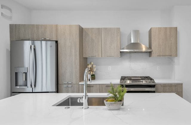 533 E Harrison Ave Unit 29, Royal Oak, MI 48067 - kitchen with wall chimney range hood, modern cabinets, light stone countertops, and stainless steel appliances