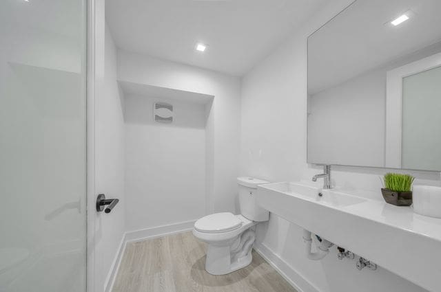533 E Harrison Ave Unit 29, Royal Oak, MI 48067 - bathroom featuring a shower, baseboards, wood finished floors, and toilet