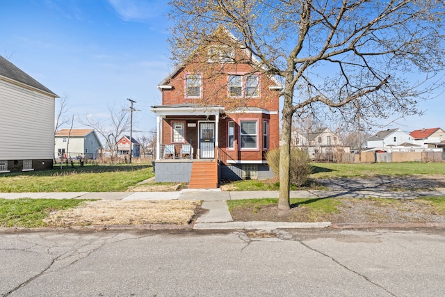 traditional-style house with a residential view, fence, a front lawn, and brick siding