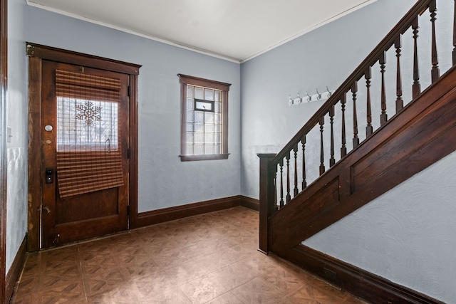 foyer entrance with ornamental molding, baseboards, and stairs