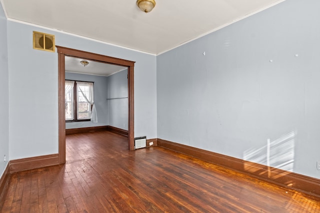 unfurnished room featuring dark wood-type flooring, visible vents, baseboards, and ornamental molding