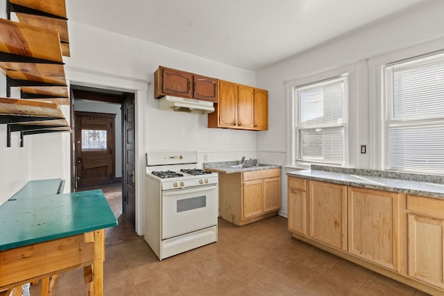 kitchen with a sink, light countertops, white gas range, and under cabinet range hood