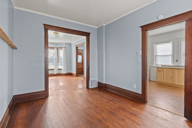 empty room with visible vents, baseboards, plenty of natural light, and hardwood / wood-style flooring