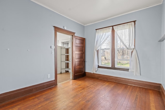 spare room featuring hardwood / wood-style flooring, baseboards, and ornamental molding