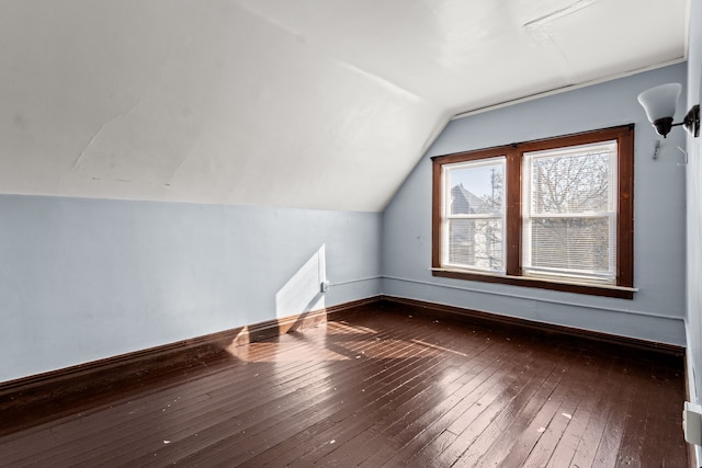 additional living space with baseboards, wood-type flooring, and lofted ceiling
