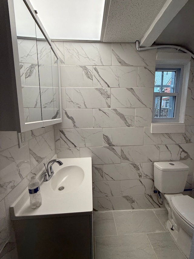 2651 Neibel St, Hamtramck, MI 48212 - bathroom with marble finish floor, vanity, tile walls, and toilet