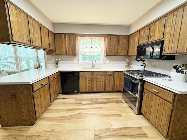 12131 Brandywine Dr, Brighton, MI 48114 - kitchen featuring black appliances, a sink, light wood-style flooring, and a peninsula