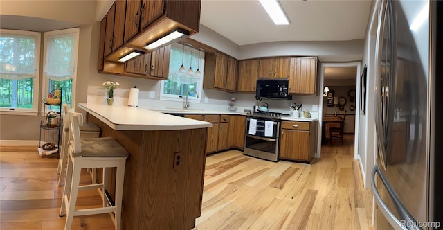12131 Brandywine Dr, Brighton, MI 48114 - kitchen with appliances with stainless steel finishes, a peninsula, light wood-style floors, light countertops, and brown cabinetry