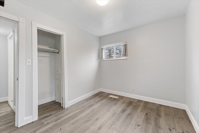 unfurnished bedroom featuring a closet, light wood-type flooring, and baseboards