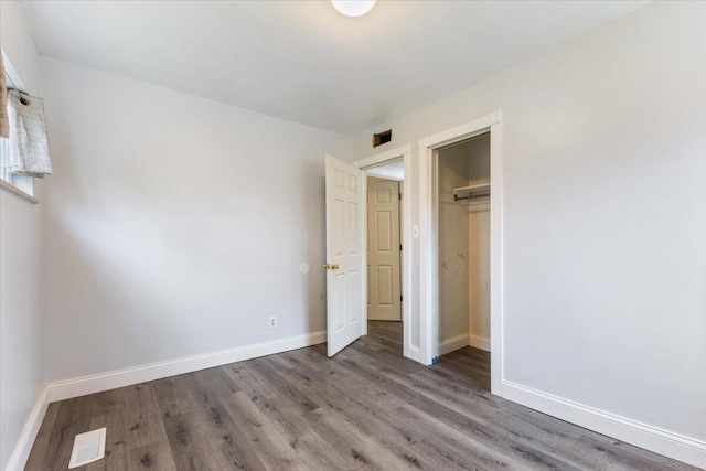 unfurnished bedroom with visible vents, baseboards, a closet, and wood finished floors