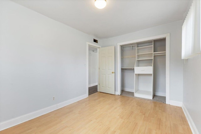 unfurnished bedroom with light wood-style flooring, a closet, baseboards, and visible vents
