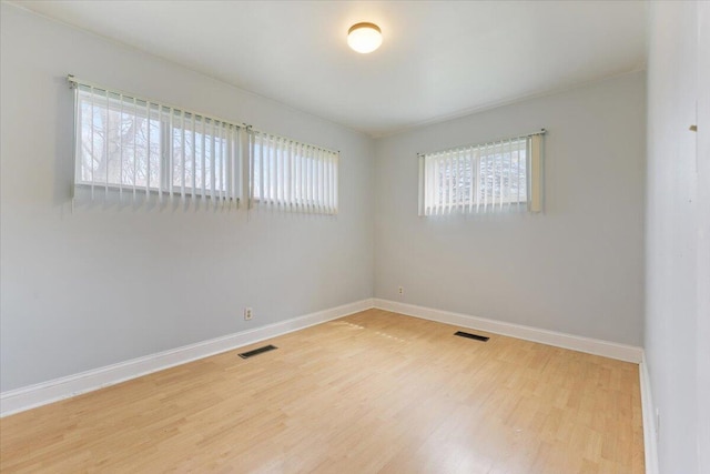 unfurnished room with a wealth of natural light, light wood-style floors, and baseboards