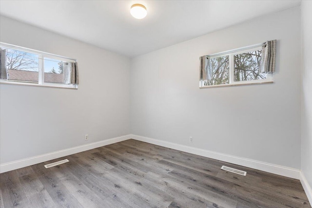 spare room featuring visible vents, baseboards, and wood finished floors