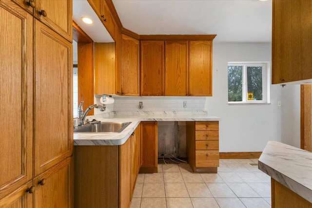 kitchen featuring brown cabinetry, light tile patterned floors, a sink, and light countertops