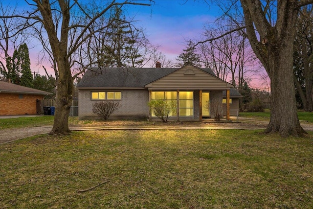 ranch-style home featuring brick siding, a lawn, and a chimney