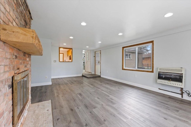 unfurnished living room featuring a fireplace, recessed lighting, wood finished floors, baseboards, and heating unit