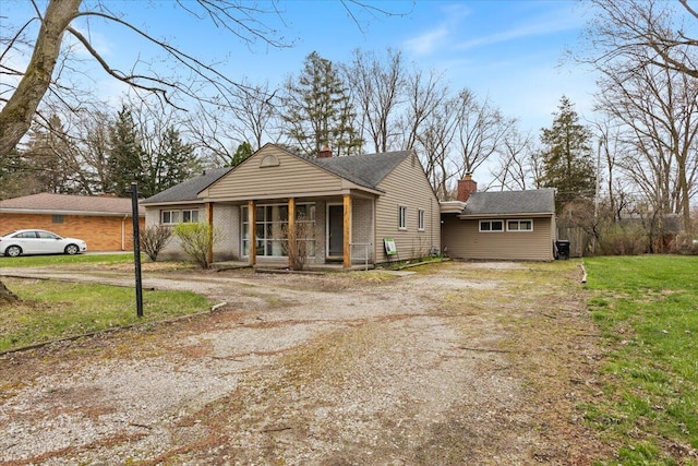view of front facade featuring a front yard, driveway, and a chimney