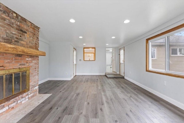 unfurnished living room featuring baseboards, recessed lighting, wood finished floors, and a fireplace