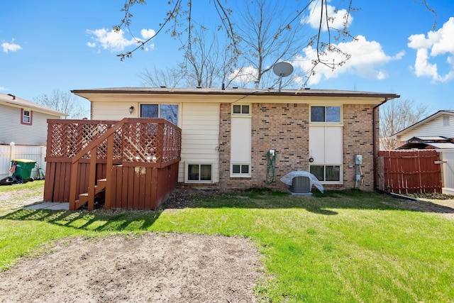 back of property featuring brick siding, fence, a yard, and a deck