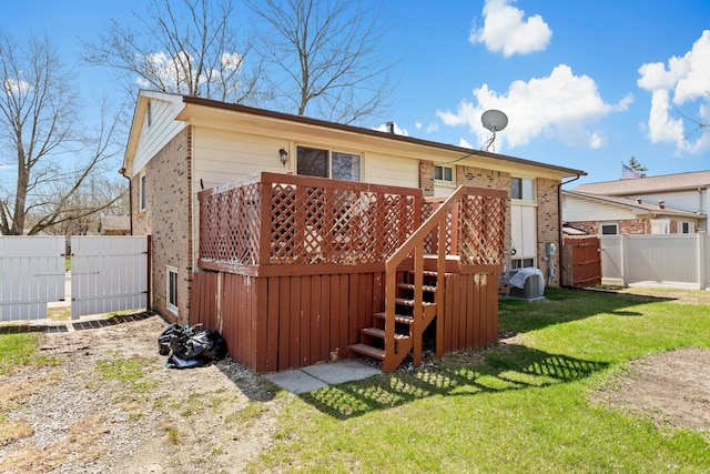 back of house featuring stairway, fence, a yard, a wooden deck, and brick siding